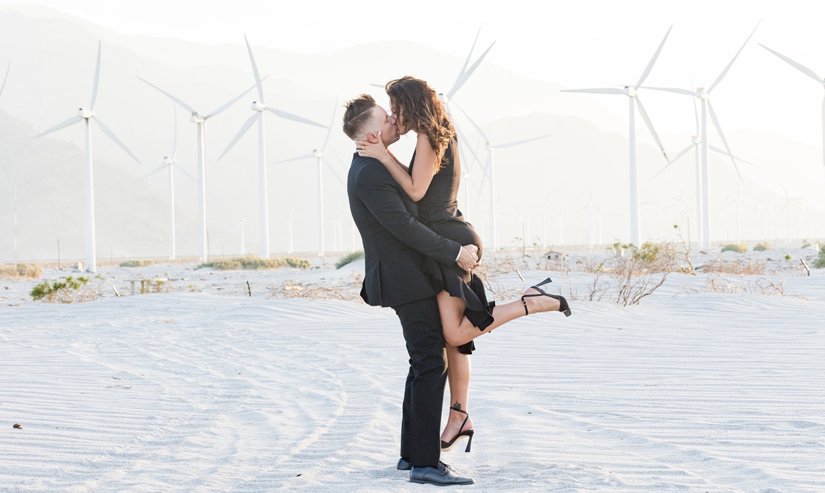 A newly married couple embraces in front of the iconic Palm Springs Windmills on their wedding day - professional photography by JL Photography