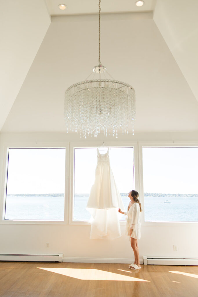 Wedding dress hanging in Belle Mer bridal suite window overlooking Newport Harbor