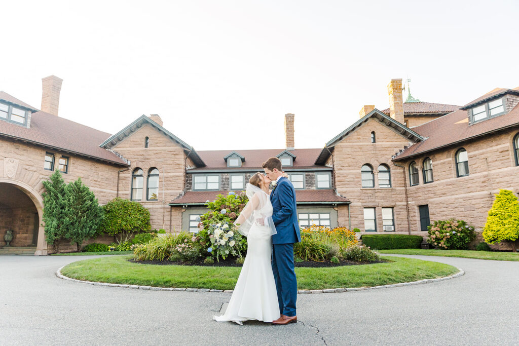 Bride and groom standing in the courtyard at OceanCliff in Newport Rhode Island with the historic stone facade behind them