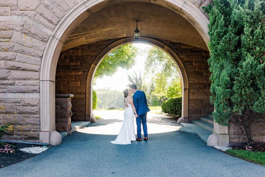 Bride and groom walking beneath the stone archway at OceanCliff in Newport Rhode Island