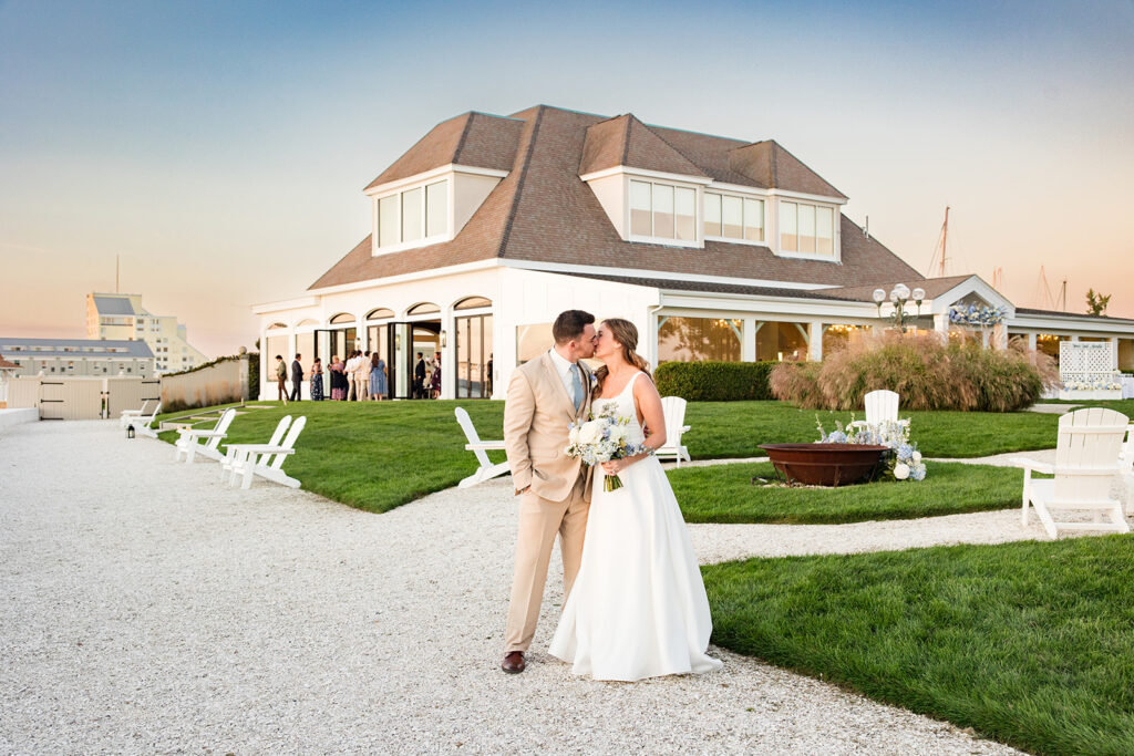 Bride and groom kissing at sunset along the waterfront at Belle Mer in Newport, Rhode Island with the Claiborne Pell Bridge in the background.