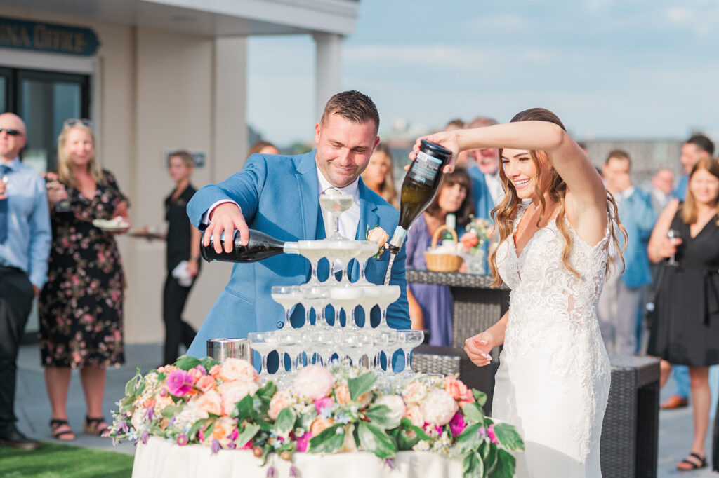 Bride and groom pour champagne into a tower during their wedding reception at Regatta Place in Newport, Rhode Island.