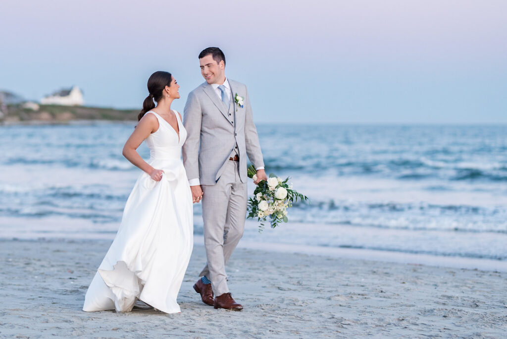 Bride and groom walking along Second Beach at sunset following their Newport Beach House wedding in Middletown, Rhode Island.
