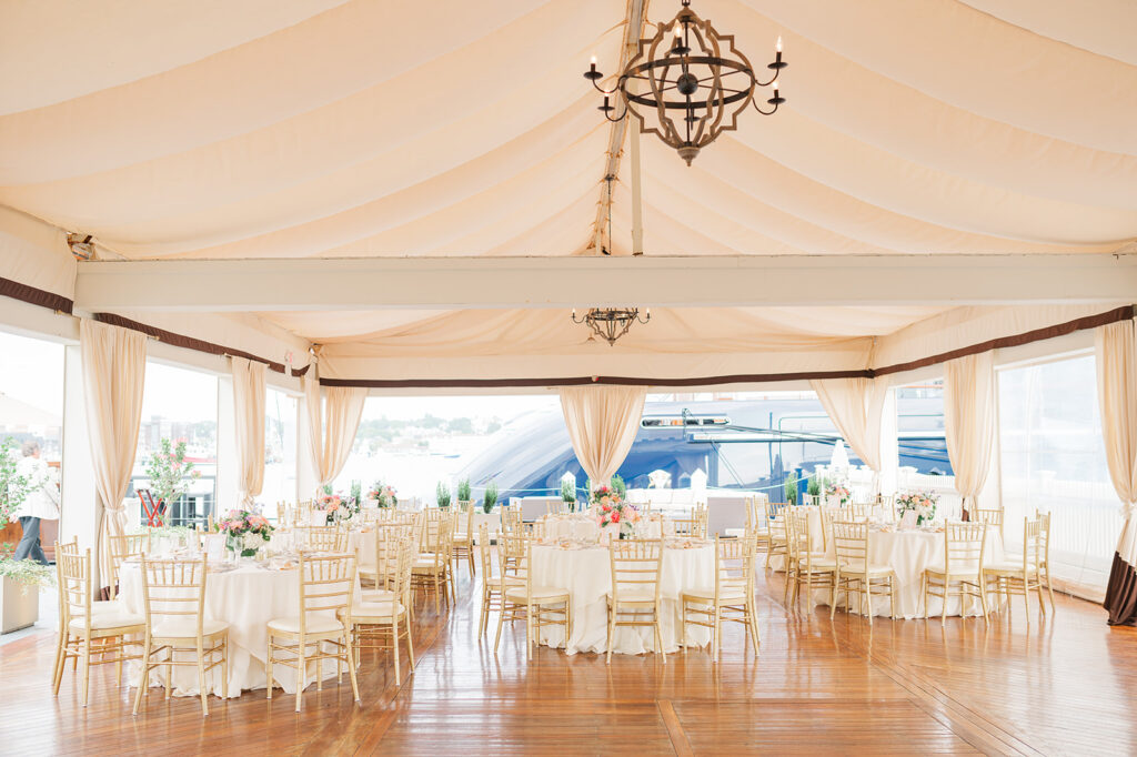 Elegant tented wedding reception at Regatta Place in Newport with harbor views and candlelit tables.