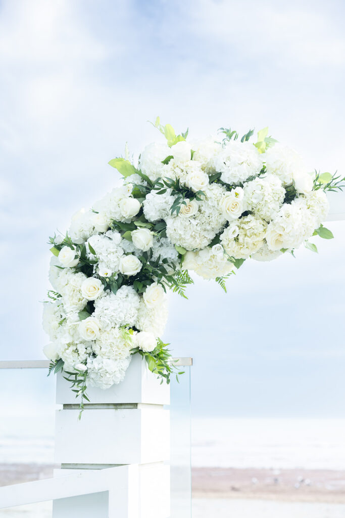 Large white hydrangea and rose ceremony arrangement overlooking the ocean designed by Cherry Hill Flowers