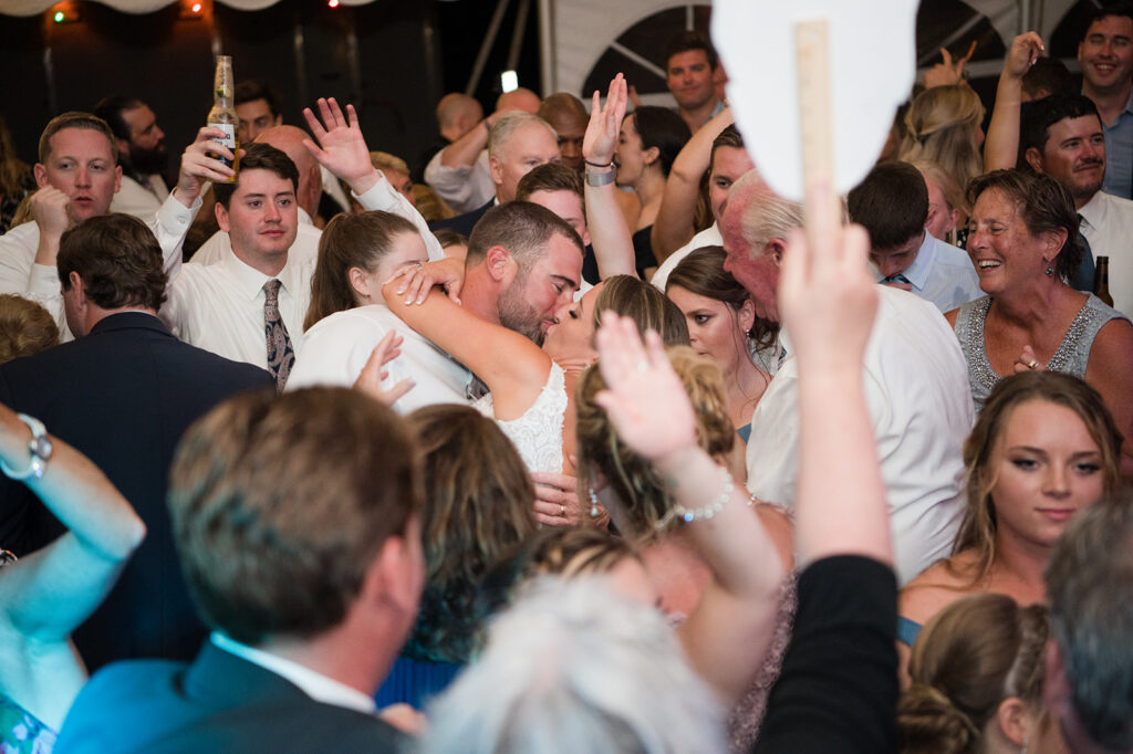 Bride and groom kissing on packed dance floor during Sullivan House Block Island wedding reception