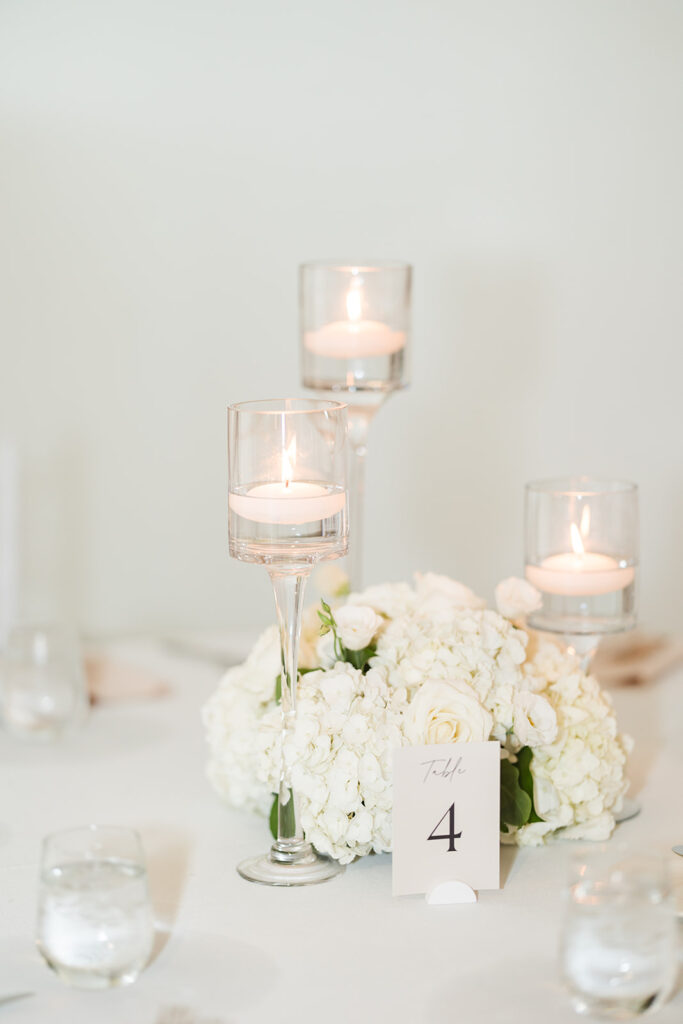Wedding table centerpiece with white hydrangeas, roses, and floating candles designed by Cherry Hill Flowers