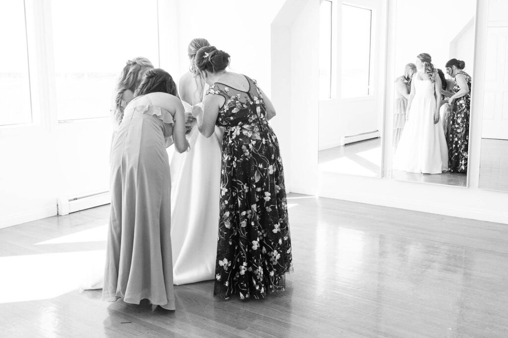 Mother helping bride into her wedding gown in the Belle Mer bridal suite