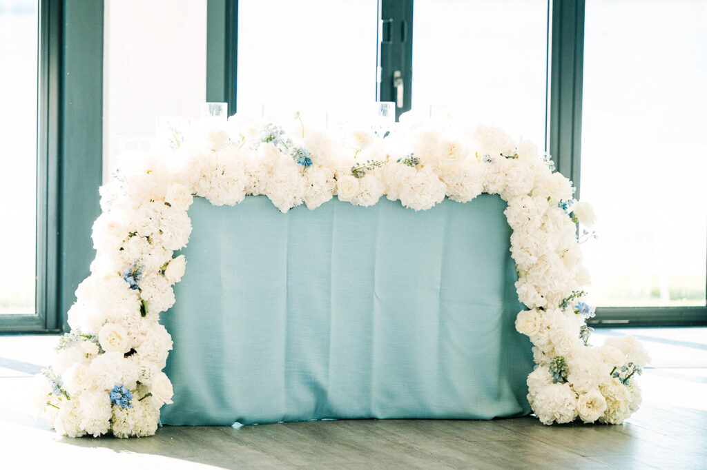 Sweetheart table with blue hydrangea floral installation at Belle Mer reception
