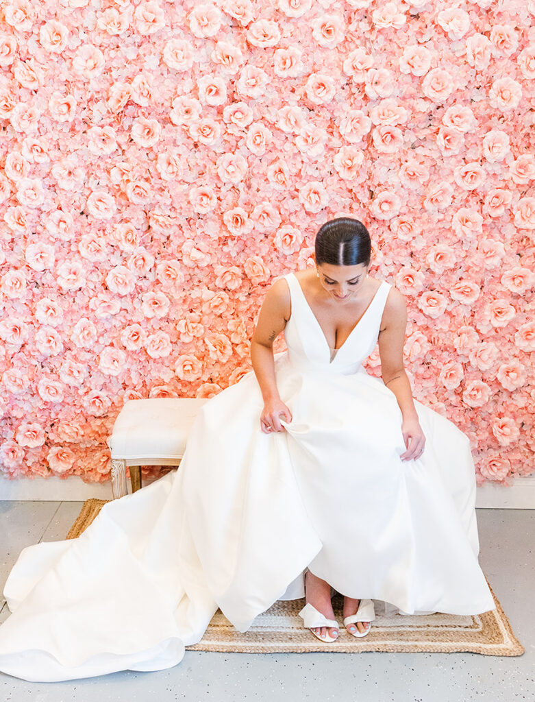 Bride sitting in a robe against a pink floral wallpaper during wedding morning