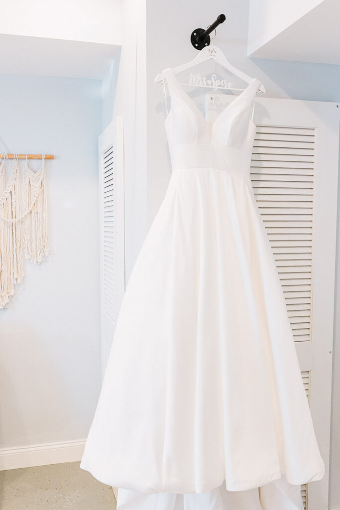 Bride’s wedding dress hanging in a bright getting ready space