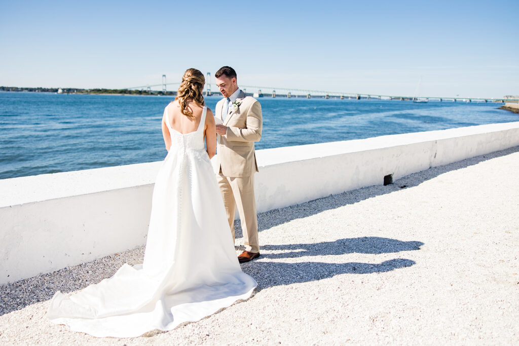 Bride and groom reading private vows along the waterfront at Belle Mer with Newport Harbor in the background
