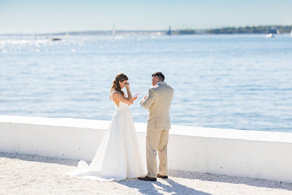 Bride wiping away tears during private vows on the Belle Mer waterfront with Newport Bridge in the background