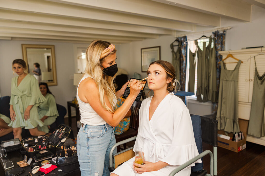Bride having makeup done while getting ready at OceanCliff in Newport