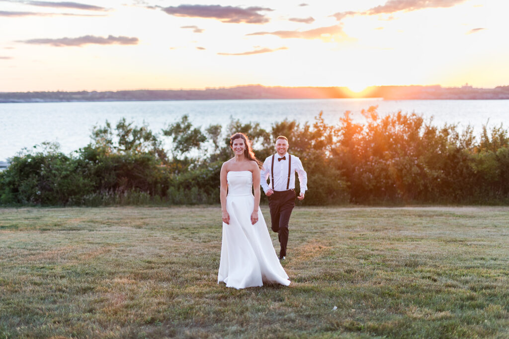 Bride and groom walking across the OceanCliff lawn at sunset