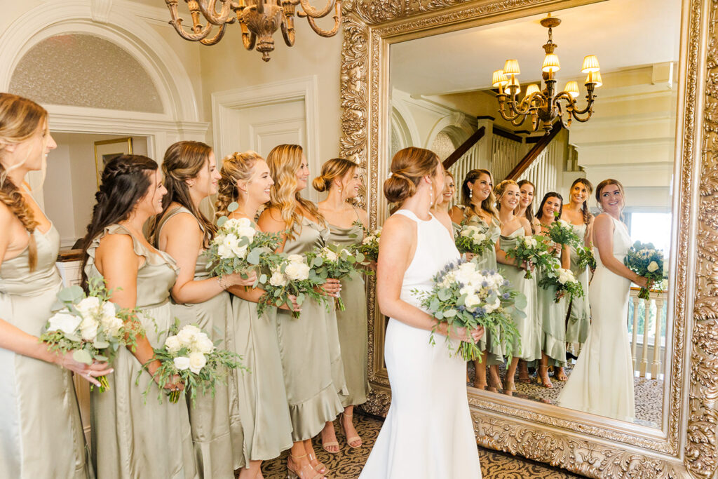 Bride and bridesmaids reflected in an ornate mirror inside OceanCliff in Newport, Rhode Island